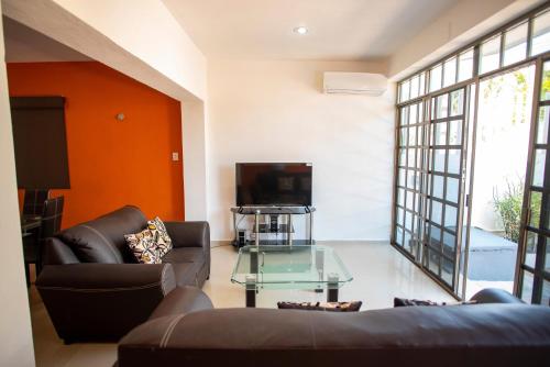 a living room with two couches and a tv at Large Villa private pool, 1 block from the beach in Chicxulub