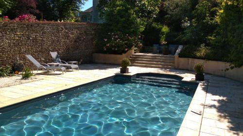 - une piscine avec 2 chaises et un mur en briques dans l'établissement Coté Marais, à Chaillé-les-Marais