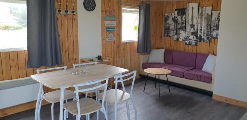- un salon avec une table et un canapé violet dans l'établissement Chalet à la campagne, à La Haye-Malherbe