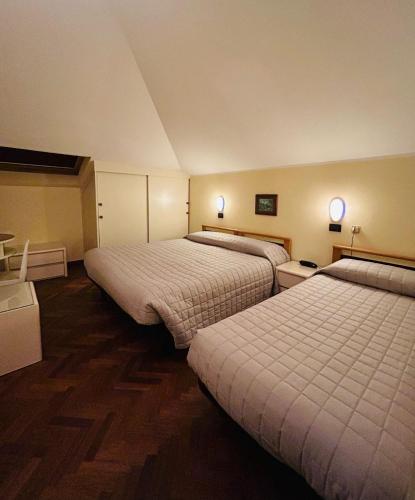 a hotel room with two beds and two tables at Hotel Milano in Cesenatico