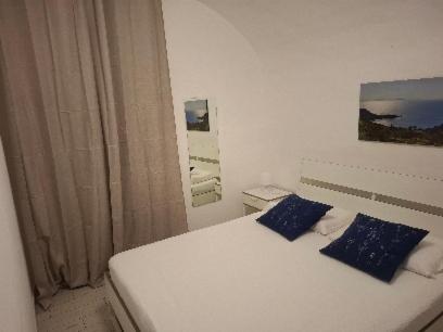 a white bed with blue pillows in a bedroom at Casa San Giorgio in Giglio Porto