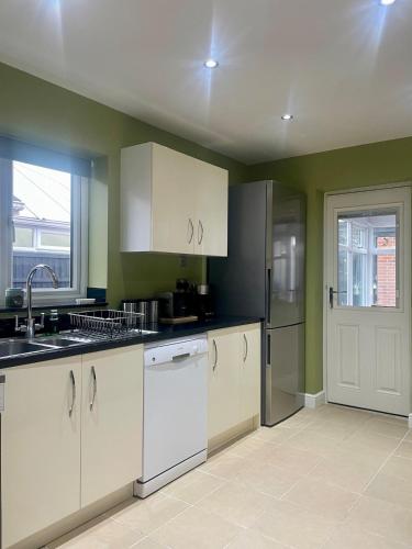 a kitchen with white cabinets and a sink at Two bedroom detached bungalow with conservatory in Bottesford