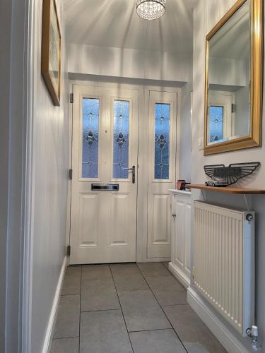 a hallway with a white door and windows at Two bedroom detached bungalow with conservatory in Bottesford