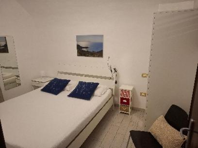 a white bedroom with a bed with blue pillows at Casa San Giorgio in Giglio Porto