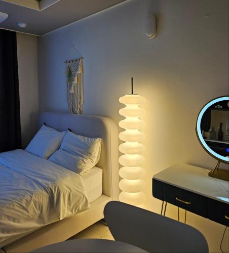 a bedroom with a bed with a mirror and a lamp at Daegu StarB&B DSR Hotel mia Guestroom in Daegu