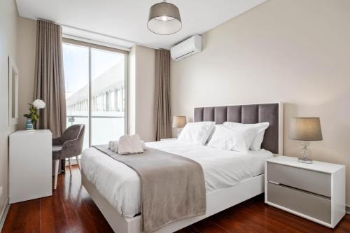 a white bedroom with a large bed and a window at SeaSide Serenity in Funchal