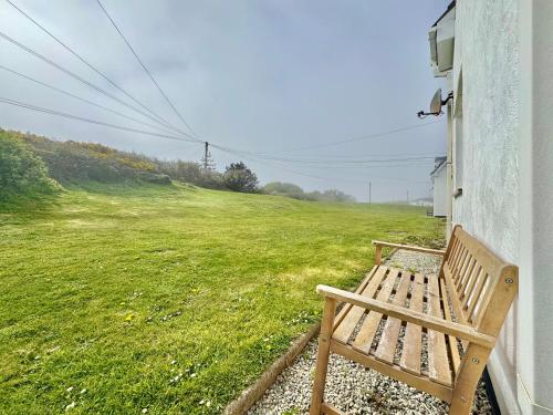 a wooden bench sitting on the side of a building next to a field at 7 Isallt Lodges-3 bed-Ground Floor-Outside seating in Trearddur
