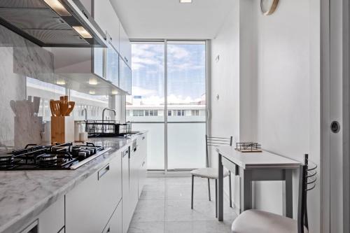 a white kitchen with a stove and a table at SeaSide Serenity in Funchal