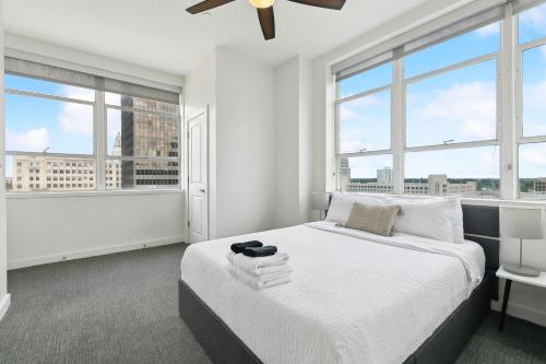 a white bedroom with large windows and a bed at Stylish Downtown High-Rise - 2BD in Baton Rouge