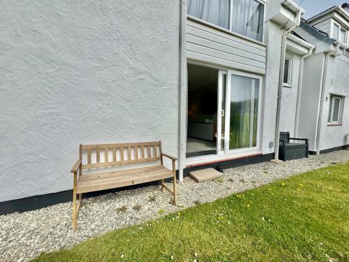 a wooden bench sitting in front of a building at 7 Isallt Lodges-3 bed-Ground Floor-Outside seating in Trearddur