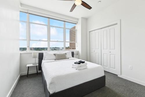 a white bedroom with a bed and a window at Stylish Downtown High-Rise - 2BD in Baton Rouge