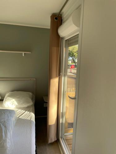une chambre avec un lit et une porte coulissante en verre dans l'établissement Mobil Home Lège Cap ferret bassin, à Lège-Cap-Ferret