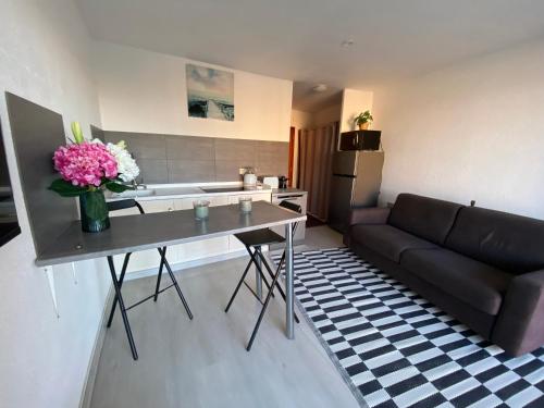 un salon avec un canapé et une table avec des fleurs dans l'établissement Appartement dans résidence France, à La Celle-sous-Gouzon