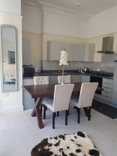a kitchen with a wooden table and white chairs at 4 Sea View in Ryde