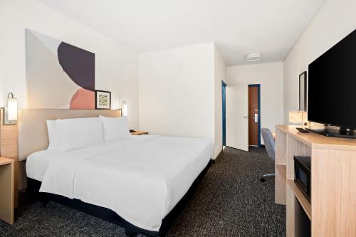モリーンにあるSpark By Hilton Moline Quad Citiesの白いベッドと薄型テレビが備わるホテルルームです。