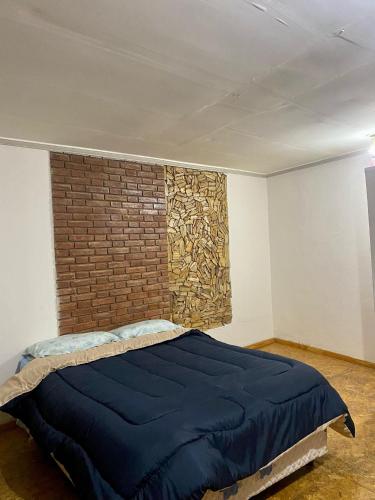 una cama en una habitación con una pared de ladrillo en EL SERENO, en San Rafael