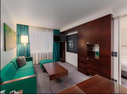 a living room with a green couch and a table at Radisson Blu Hotel Olümpia in Tallinn
