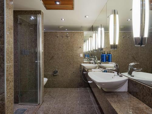 a bathroom with three sinks and a shower at Radisson Blu Hotel Olümpia in Tallinn