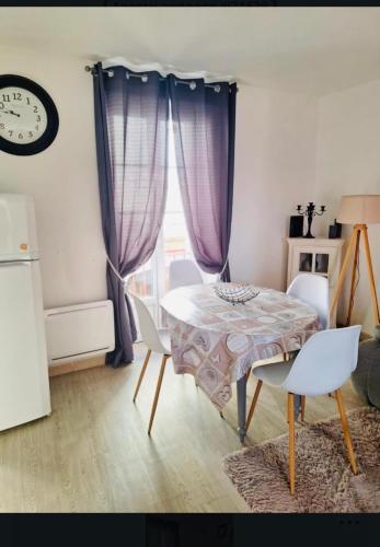 une salle à manger avec une table, des chaises et une horloge dans l'établissement Appartement 2-4 pers, à Souillac