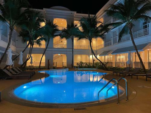 a large swimming pool in front of a building with palm trees at Outrigger Koh Samui Beach Resort - SHA Extra Plus in Lamai