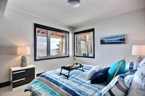 ein Schlafzimmer mit einem Bett und zwei Fenstern in der Unterkunft Villa St-Laurent et spa - Au coeur de Charlevoix ! in La Malbaie