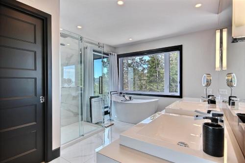 ein Badezimmer mit 2 Waschbecken, einer Dusche und einer Badewanne in der Unterkunft Villa St-Laurent et spa - Au coeur de Charlevoix ! in La Malbaie
