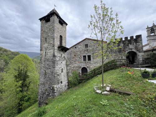 an old stone building on a hill with a tree at Incantevole rifugio nel castello di Ahrensperg in Pulfero