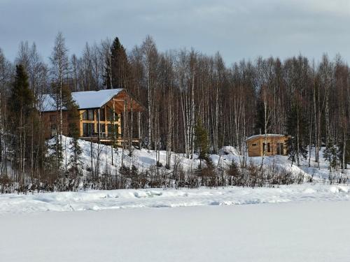 a log cabin in the snow next to a lake at New modern log villa in Äkäsjoensuu