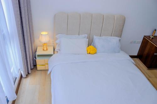 a bedroom with a bed with a yellow stuffed animal on it at Two Rivers - Riverbank Apartment One Bedroom in Nairobi