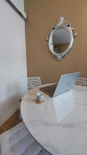 a laptop sitting on a white table with a mirror at Le Réverbère, appartement de vacances in Lectoure