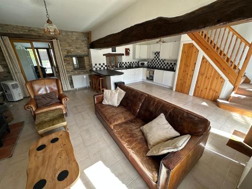 un salon avec un canapé marron et une cuisine dans l'établissement Kastellbriant Cottage, à Saint-Aubin-des-Châteaux