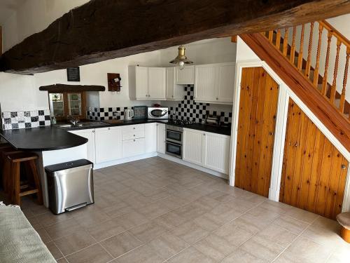 une cuisine avec des placards blancs et un escalier en bois dans l'établissement Kastellbriant Cottage, à Saint-Aubin-des-Châteaux