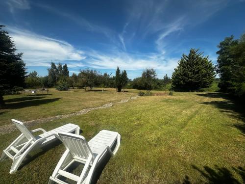 deux chaises blanches assises dans un champ d'herbe dans l'établissement Kastellbriant Cottage, à Saint-Aubin-des-Châteaux