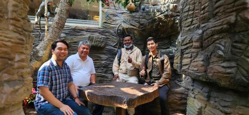 a group of men standing next to a wooden table at S & B Dreams House in Munnar