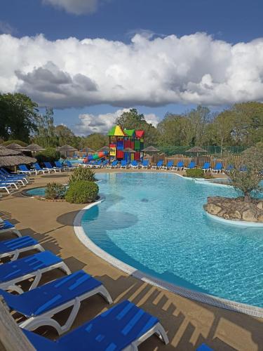 une piscine dans un complexe hôtelier avec des chaises longues et un parc aquatique dans l'établissement Mobil-home 4 à 6 personnes camping paradis 4 étoiles, à Clohars-Carnoët