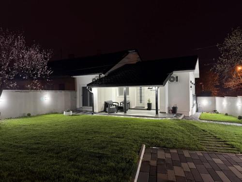 a white house with a lawn at night at Apartman 28 in Arandjelovac