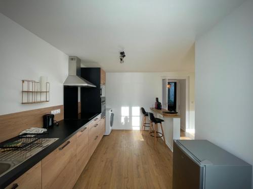 une cuisine avec des murs blancs et un comptoir noir dans l'établissement Maison centre bourg Echiré, à Échiré