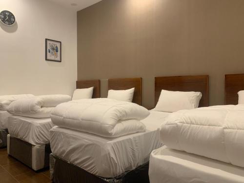 a room with three beds with white sheets at فيلا المنزل in Makkah