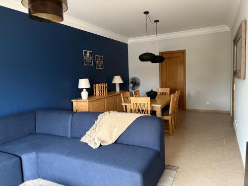 a living room with a blue couch and a dining room at Fairviews Boavista , Boavista golf and spa resort Lagos in Lagos