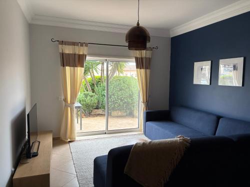 a living room with a blue couch and a sliding glass door at Fairviews Boavista , Boavista golf and spa resort Lagos in Lagos