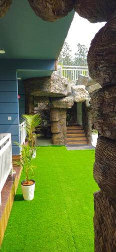 a yard with green grass and a stone wall at S & B Dreams House in Munnar