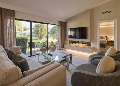 a living room with two couches and a tv at The Edwardian at PGA, designer's Cottage in Palm Beach Gardens
