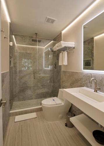 a bathroom with a shower and a toilet and a sink at The Edwardian at PGA, designer's Cottage in Palm Beach Gardens