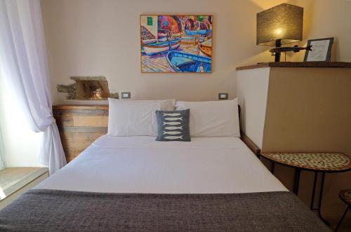 a bedroom with a white bed with a painting on the wall at Allo Scalo Dei Mille in Riomaggiore