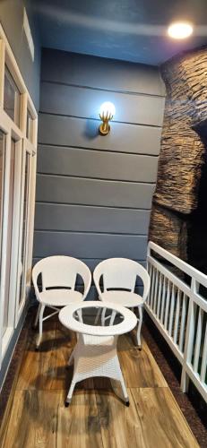 two white chairs and a table on a porch at S & B Dreams House in Munnar