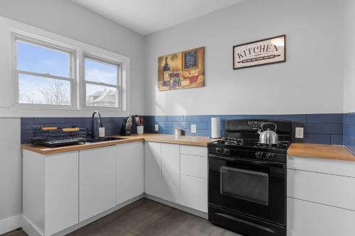 a kitchen with a black stove and white cabinets at Grand Rapids Gem - Near Heart of DT - Sleeps 10 in Grand Rapids