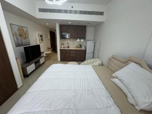 Una cama blanca grande en una habitación con cocina. en Cozy beautiful studio, en Sharjah
