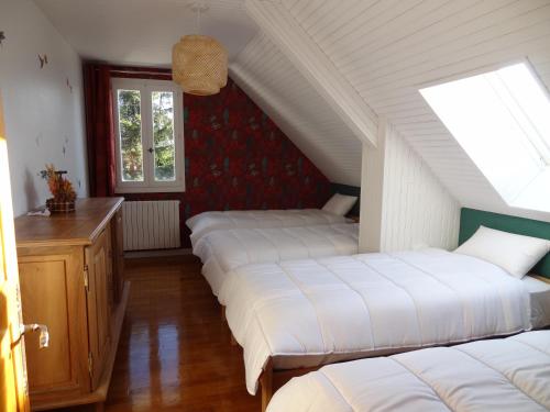 Cette chambre mansardée comprend 3 lits et une fenêtre. dans l'établissement Gîte Chez Léon, à La Chaze-de-Peyre