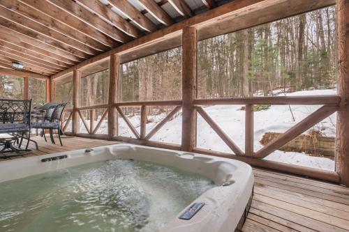 a jacuzzi tub in a screened in porch with a table at Lucky Log Cabin Hottub fireplace 12min to Mt Snow in Wardsboro