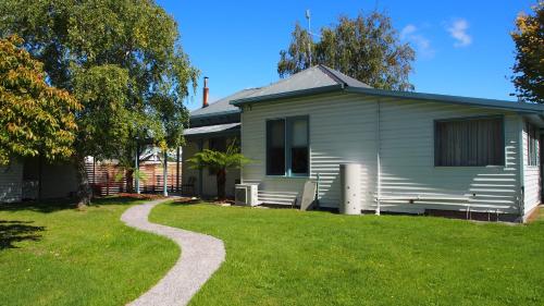 a house with a gravel path in front of it at Strahan Retreat Holiday Park in Strahan